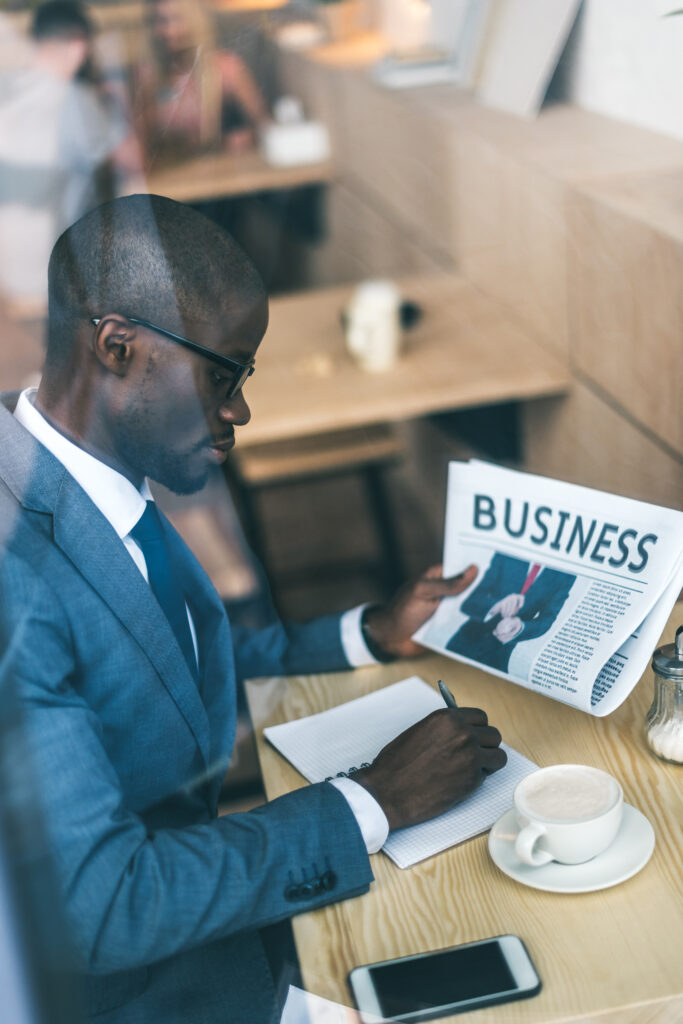 serious handsome african american businessman with newspaper working in coffee shop